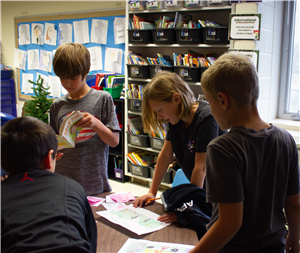 kids standing at table explaining drawings 